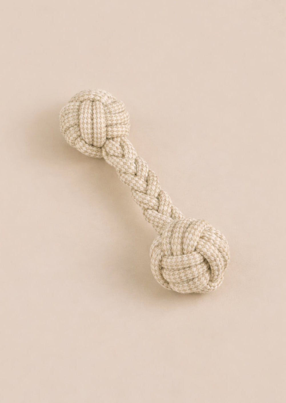 Textured dog toy with braided design on a beige background