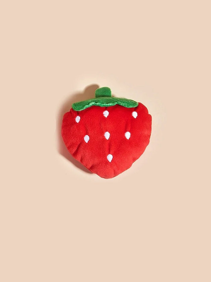 Red strawberry-shaped object with white polka dots on a beige background