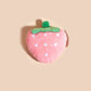 Plush strawberry toy on a beige background